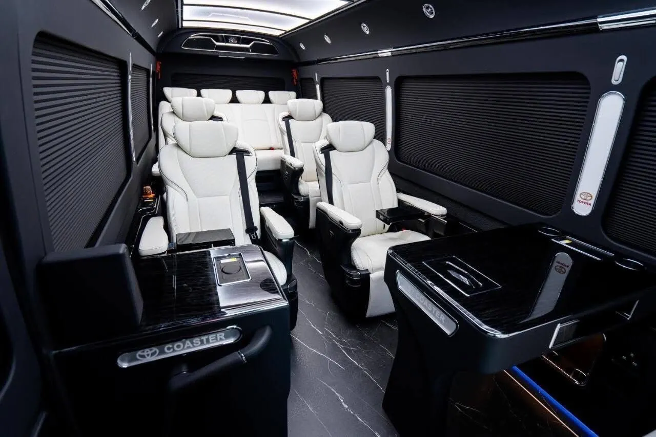 Toyota Coaster luxury cabin with white captain's chairs and marble floor
